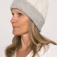 Woman wearing a gray and white knit beanie on a plain background