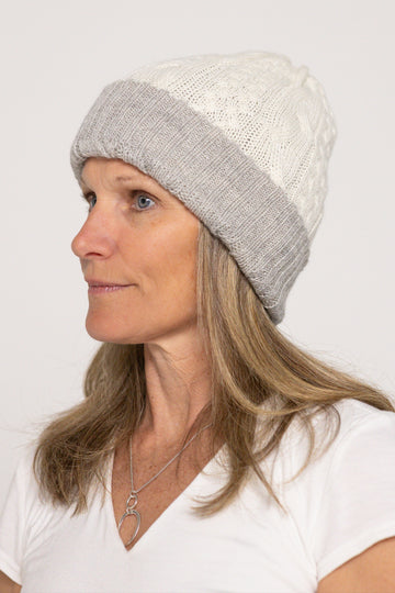 Woman wearing a gray and white knit beanie on a plain background