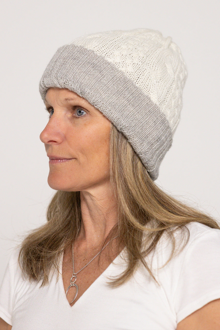 Woman wearing a gray and white knit beanie on a plain background