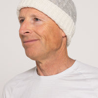 Person wearing a gray knit beanie and white shirt against a plain background