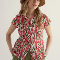 Woman wearing a floral blouse and straw hat on a plain background