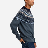 Man wearing a dark gray sweater with a patterned design on a white background