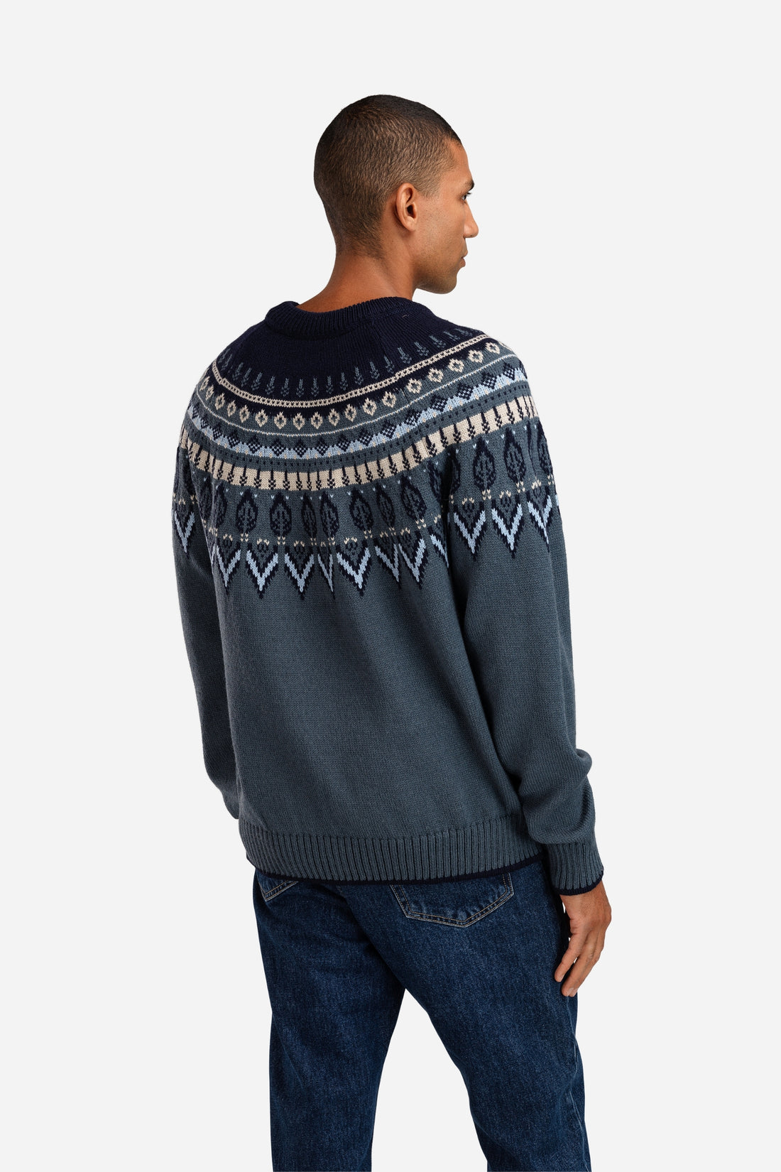 Man wearing a dark blue sweater with a patterned design on a white background