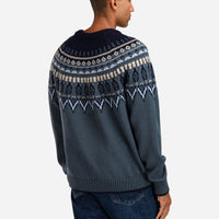 Man wearing a dark blue sweater with a patterned design on a white background