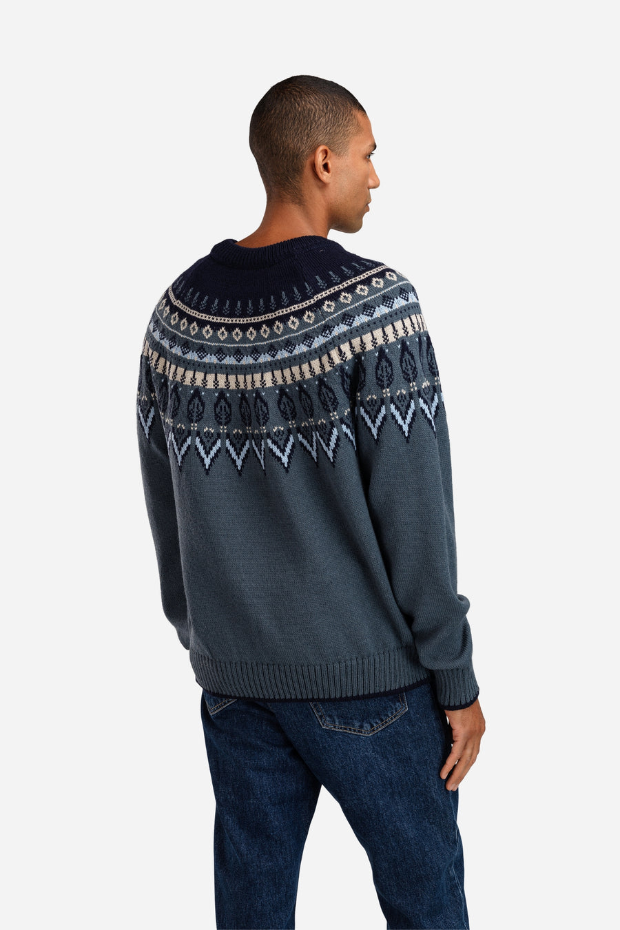 Man wearing a dark blue sweater with a patterned design on a white background