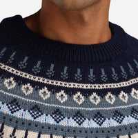 Navy blue sweater with white and light blue pattern worn by a person