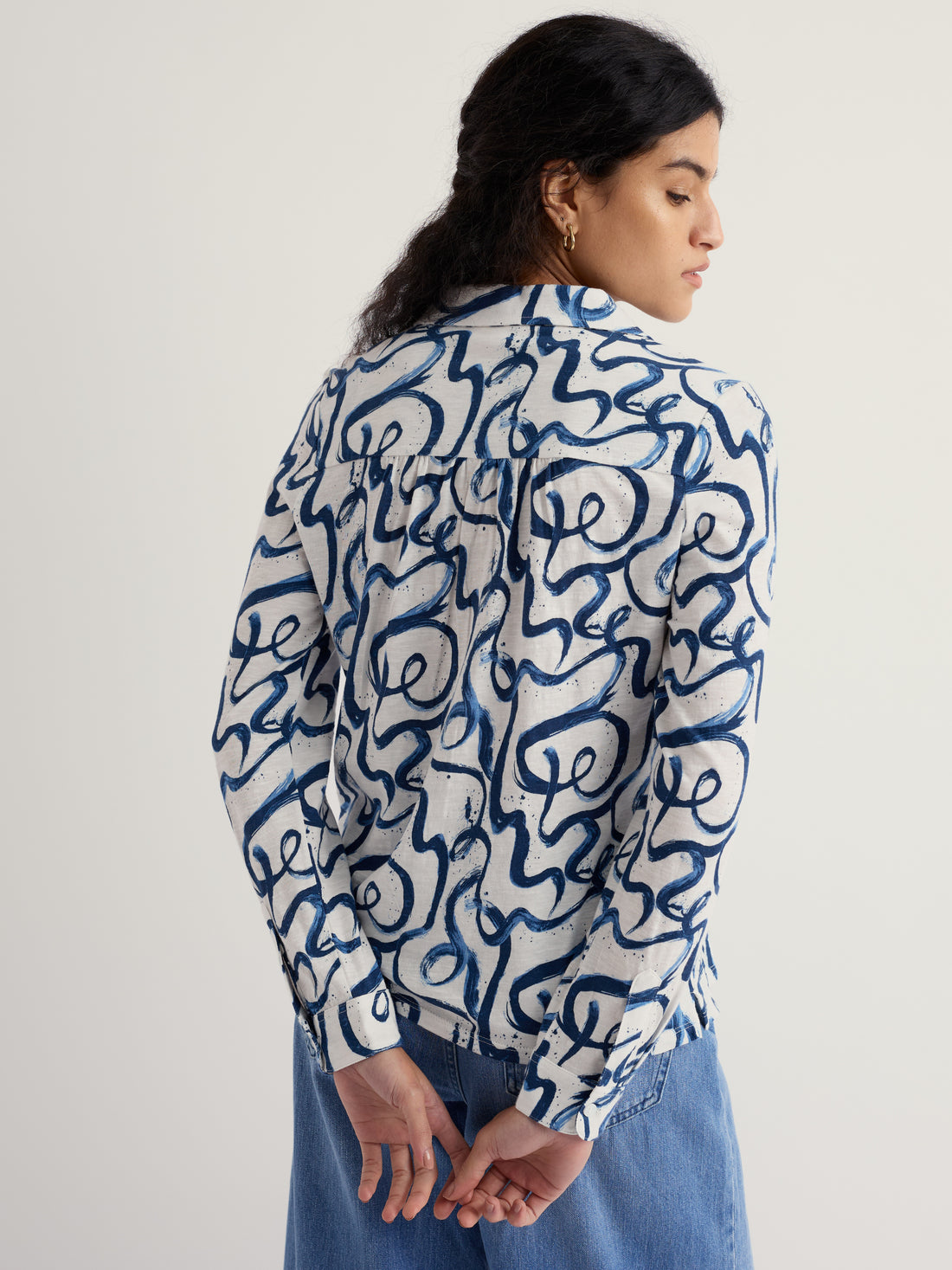 Person wearing a blue and white patterned shirt on a plain background