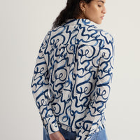 Person wearing a blue and white patterned shirt on a plain background