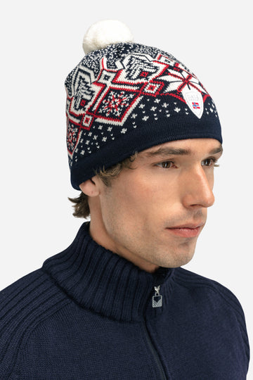 Man wearing a patterned beanie with a white pom-pom on a white background