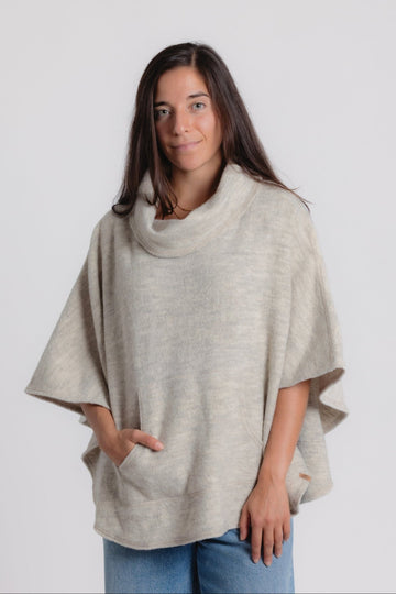 Woman wearing a beige poncho against a white background