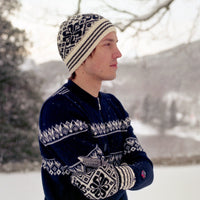 Person wearing a patterned knit sweater and hat in a snowy landscape